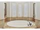 A soaking tub surrounded by tile, plantation shutters and large mirrors at 5291 S Bradshaw Pl, Chandler, AZ 85249