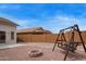 This backyard features a gravel yard, block wall, fire pit, and wooden swing set at 695 S 221St Dr, Buckeye, AZ 85326