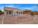 This backyard features a gravel yard, block wall, wooden swing set, and covered patio at 695 S 221St Dr, Buckeye, AZ 85326