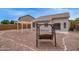 This backyard features a gravel yard, block wall, wooden swing set, and covered patio at 695 S 221St Dr, Buckeye, AZ 85326