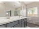 Bathroom with a dual sink vanity, large mirror, and tiled walk-in shower at 695 S 221St Dr, Buckeye, AZ 85326