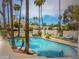 Community swimming pool with palm trees, lounge chairs, tables, and mountain views in a gated area at 8653 S 51St St # 2, Phoenix, AZ 85044