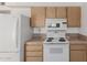 Classic kitchen layout with white appliances, light wood cabinets, and functional design at 9265 N 111Th Ave, Sun City, AZ 85351