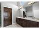 Elegant bathroom featuring double sinks, a vanity with dark wood cabinets and a well-lit mirror at 11131 E Becker Ln, Scottsdale, AZ 85259