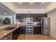 Modern kitchen with stainless steel appliances, dark cabinets, breakfast bar, and tiled flooring at 1125 S Larkspur St, Gilbert, AZ 85296