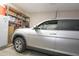 Clean one-car garage featuring white walls, bright lighting, shelving units, and a refrigerator for extra space at 1210 W Betty Elyse Ln, Phoenix, AZ 85023