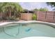 A backyard swimming pool with greenery and mature palm trees at 1210 W Betty Elyse Ln, Phoenix, AZ 85023