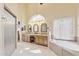 Well-lit bathroom featuring dual vanities, arched window, and a soaking tub at 1241 W Lobster Trap Dr, Gilbert, AZ 85233