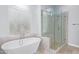 Spa-like bathroom featuring a soaking tub, a glass-enclosed shower with stylish tile work, and a bright window at 1442 W Laurel Ave, Gilbert, AZ 85233