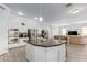 Open concept kitchen with stainless steel appliances, large island, white cabinets, and tile flooring, flowing into the living room at 1442 W Laurel Ave, Gilbert, AZ 85233