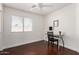 Bedroom featuring a ceiling fan, modern lamp, a glass desk, a chair, hard wood floors and a large window at 15805 W Morning Glory St, Goodyear, AZ 85338