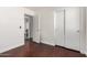 Bedroom featuring hard wood floors, baseboards, a closet, and an open door to an ensuite bathroom at 15805 W Morning Glory St, Goodyear, AZ 85338