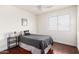 Bright bedroom featuring a full-sized bed, dark wood floors, a modern lamp, and a large window at 15805 W Morning Glory St, Goodyear, AZ 85338