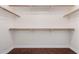 Walk-in closet featuring hardwood floor, baseboards, and built-in wooden hanging rods and shelves at 15805 W Morning Glory St, Goodyear, AZ 85338