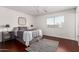Comfortable main bedroom featuring a queen-sized bed with lamps on mirrored nightstands, ceiling fan and wood floors at 15805 W Morning Glory St, Goodyear, AZ 85338