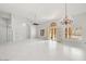 A large living room featuring white tile flooring, a chandelier, and doors leading to an outdoor space at 16219 S 14Th Way, Phoenix, AZ 85048