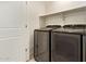 This is a laundry room with newer model washer and dryer on tile flooring with shelf and a white door at 19951 W Wilson St, Buckeye, AZ 85326