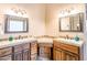 Bright bathroom featuring dual sinks, custom wood cabinets, and decorative mirrors at 20439 E Palomino Dr, Queen Creek, AZ 85142