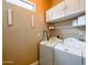 Bright laundry room featuring washer, dryer, overhead storage, and ironing board at 20439 E Palomino Dr, Queen Creek, AZ 85142