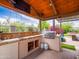 Relax in this outdoor kitchen with built-in grill, sink, and TV perfect for entertaining on the patio at 20439 E Palomino Dr, Queen Creek, AZ 85142