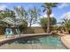 Backyard pool with a stone waterfall, lush landscaping, and two chairs under an umbrella at 21362 E Puesta Del Sol Rd, Queen Creek, AZ 85142