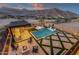 Aerial view showcasing a pool, spa, outdoor kitchen, fire pit, desert landscaping, and mountain views at 21632 W Hillcrest Blvd, Buckeye, AZ 85396