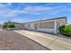 Long home exterior with driveway, rock landscaping, and a covered parking area at 2241 N Nicklaus Dr, Mesa, AZ 85215