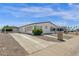 Charming single-story home features a white exterior, low maintenance landscaping, and covered carport at 2241 N Nicklaus Dr, Mesa, AZ 85215
