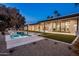 Backyard showcasing a pool and spa against a gravel yard; palm trees dot the horizon at twilight at 23002 N Country Club Trl, Scottsdale, AZ 85255