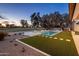 Backyard showcasing a pool, spa, and putting green against the backdrop of a golf course at twilight at 23002 N Country Club Trl, Scottsdale, AZ 85255