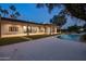 Backyard featuring a modern pool and spa with a covered patio and fireplace; palm trees dot the horizon at sunset at 23002 N Country Club Trl, Scottsdale, AZ 85255