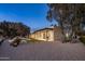 Backyard featuring a pool, spa, and covered patio against a gravel yard; palm trees dot the horizon at twilight at 23002 N Country Club Trl, Scottsdale, AZ 85255