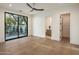 A sunlit bedroom boasts hardwood floors, a modern ceiling fan, and a sliding glass door leading to an outdoor space at 23002 N Country Club Trl, Scottsdale, AZ 85255