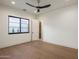 A bright and airy bedroom features hardwood floors, a modern ceiling fan, and a large window with natural light at 23002 N Country Club Trl, Scottsdale, AZ 85255