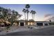 Stylish desert home boasts well-manicured landscaping, dark garage doors, a red tile roof, and towering palms at 23002 N Country Club Trl, Scottsdale, AZ 85255