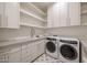 Bright laundry room featuring modern washer/dryer units, sleek cabinetry, and a sink at 23002 N Country Club Trl, Scottsdale, AZ 85255