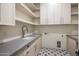 Well-lit laundry room features modern gray countertops, shaker cabinets and geometric pattern tile flooring at 23002 N Country Club Trl, Scottsdale, AZ 85255