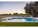 A backyard showcases a refreshing pool, integrated spa, and a tranquil golf course backdrop at sunset at 23002 N Country Club Trl, Scottsdale, AZ 85255