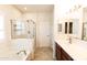 Bright bathroom featuring a tub, walk-in shower, and vanity with modern fixtures at 25640 N 108Th Dr, Peoria, AZ 85383