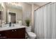 Bright bathroom features a sink with dark wood cabinet and tub-shower with a stylish striped curtain at 26391 N 107Th Dr, Peoria, AZ 85383