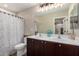 A spacious bathroom featuring double sinks with dark cabinets and a shower tub with stylish patterned curtain at 26391 N 107Th Dr, Peoria, AZ 85383