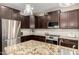 Well-equipped kitchen boasts stainless steel appliances, dark cabinetry, granite countertops, and decorative lighting at 26391 N 107Th Dr, Peoria, AZ 85383