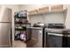 Functional laundry area with stainless steel appliances, storage shelves, and tiled floor for convenient home chores at 26391 N 107Th Dr, Peoria, AZ 85383