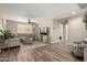 Open-concept living room featuring wood-look floors, a ceiling fan and a cozy gray sectional with decorative pillows at 26391 N 107Th Dr, Peoria, AZ 85383