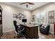 Home office with a wooden desk, a comfortable black office chair, and plantation shutters at 26391 N 107Th Dr, Peoria, AZ 85383