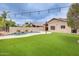 Expansive backyard featuring artificial turf, a swimming pool with rock features, and a covered patio at 4041 W Hackamore Dr, Phoenix, AZ 85083