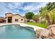 Inviting pool with rock waterfall feature, surrounded by artificial turf and a walkway to the house at 4041 W Hackamore Dr, Phoenix, AZ 85083