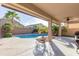 Backyard view from under the patio showing the inviting pool surrounded by lush landscaping and block wall at 43615 W Roth Rd, Maricopa, AZ 85138