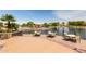Charming lakeside area features inviting tables and chairs, enhanced by lush landscaping, offering a relaxing community gathering spot at 43615 W Roth Rd, Maricopa, AZ 85138