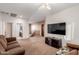 Spacious living room featuring a large television, neutral carpeting, and a ceiling fan at 43615 W Roth Rd, Maricopa, AZ 85138